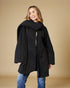Woman wearing a black coat against a beige background