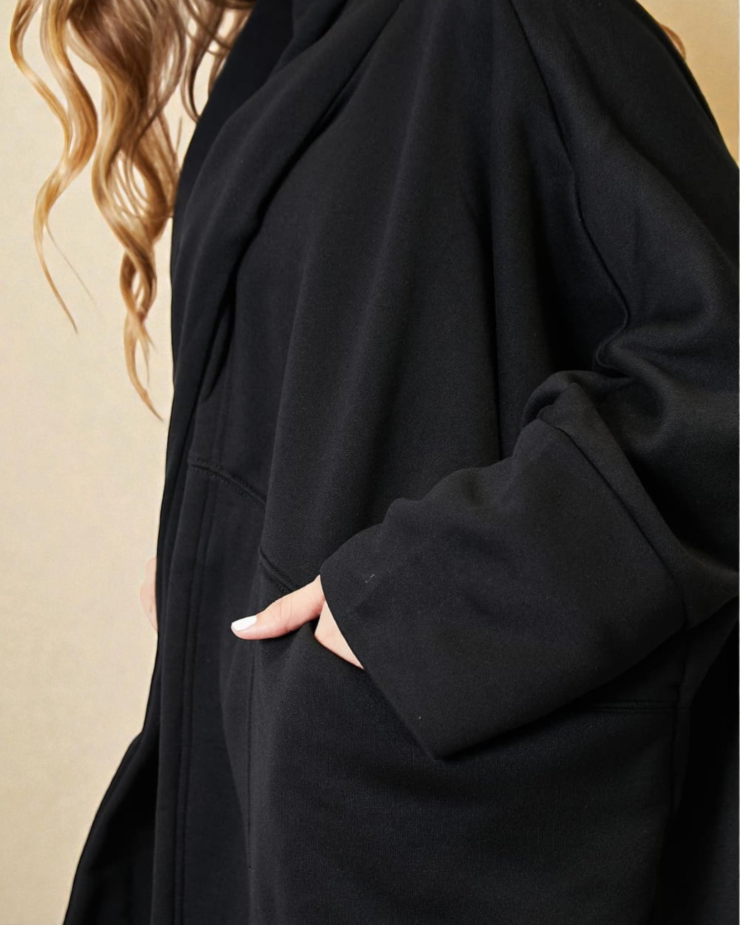 Person wearing a black coat with a beige background