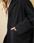 Person wearing a black coat with a beige background