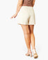 A model from the back wearing high-waisted, off-white shorts, a brown top, and beige high-heeled sandals against a plain white background.