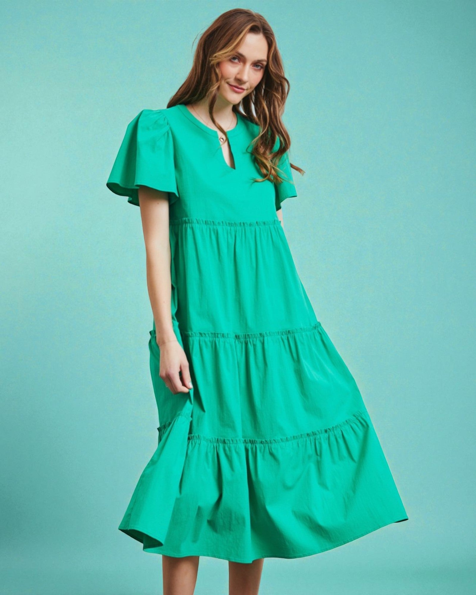 Woman wearing a green dress against a teal background