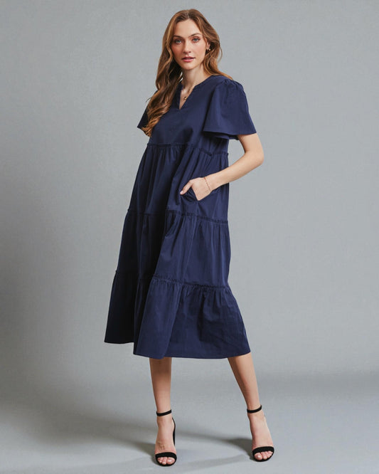 Woman wearing a navy blue dress against a gray background