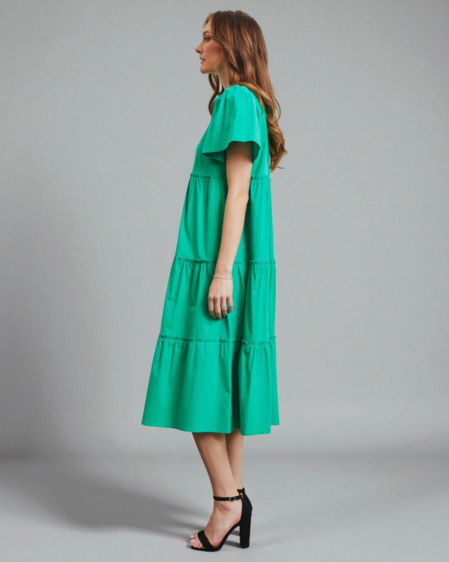 Woman wearing a green dress against a gray background