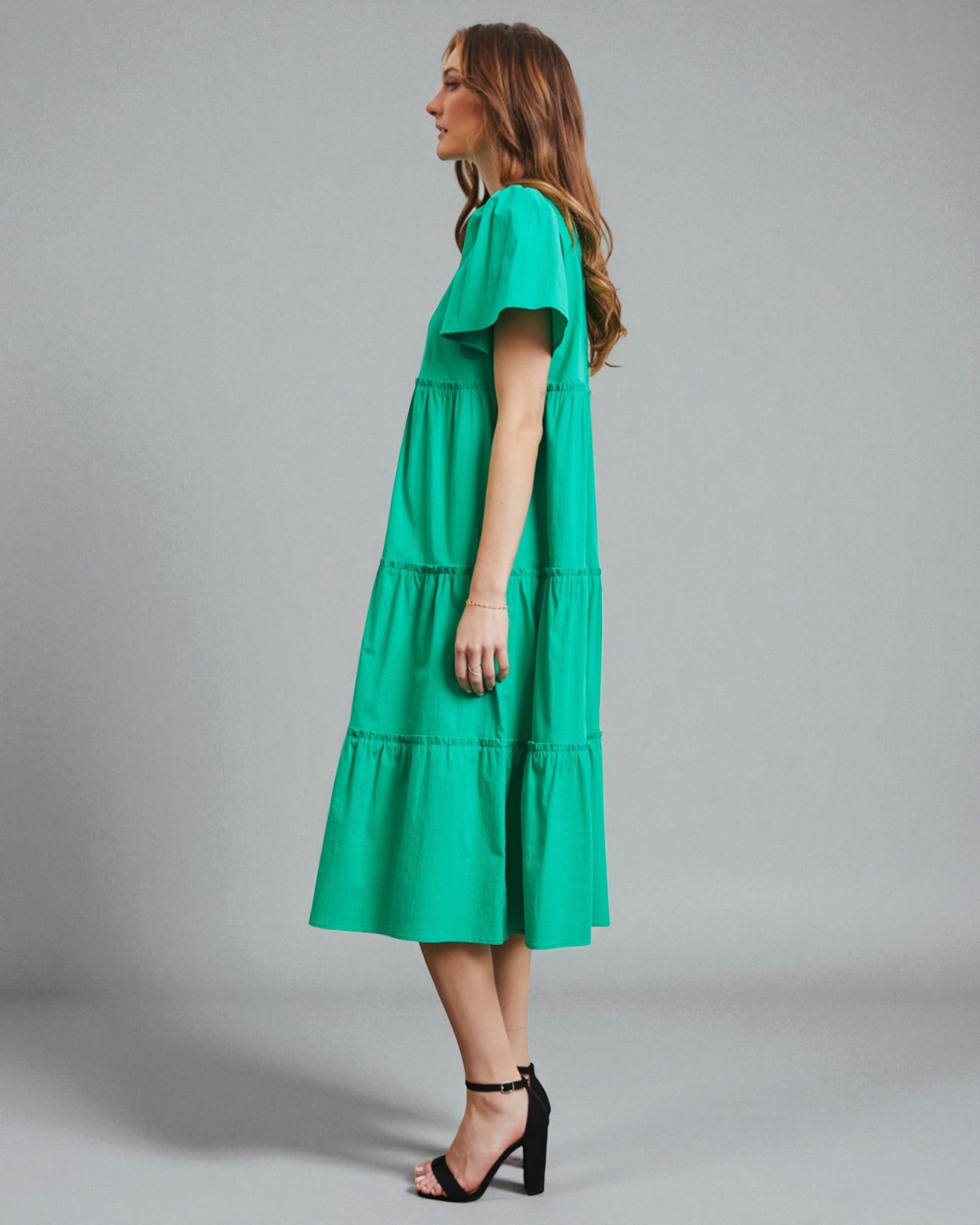 Woman wearing a green dress against a gray background