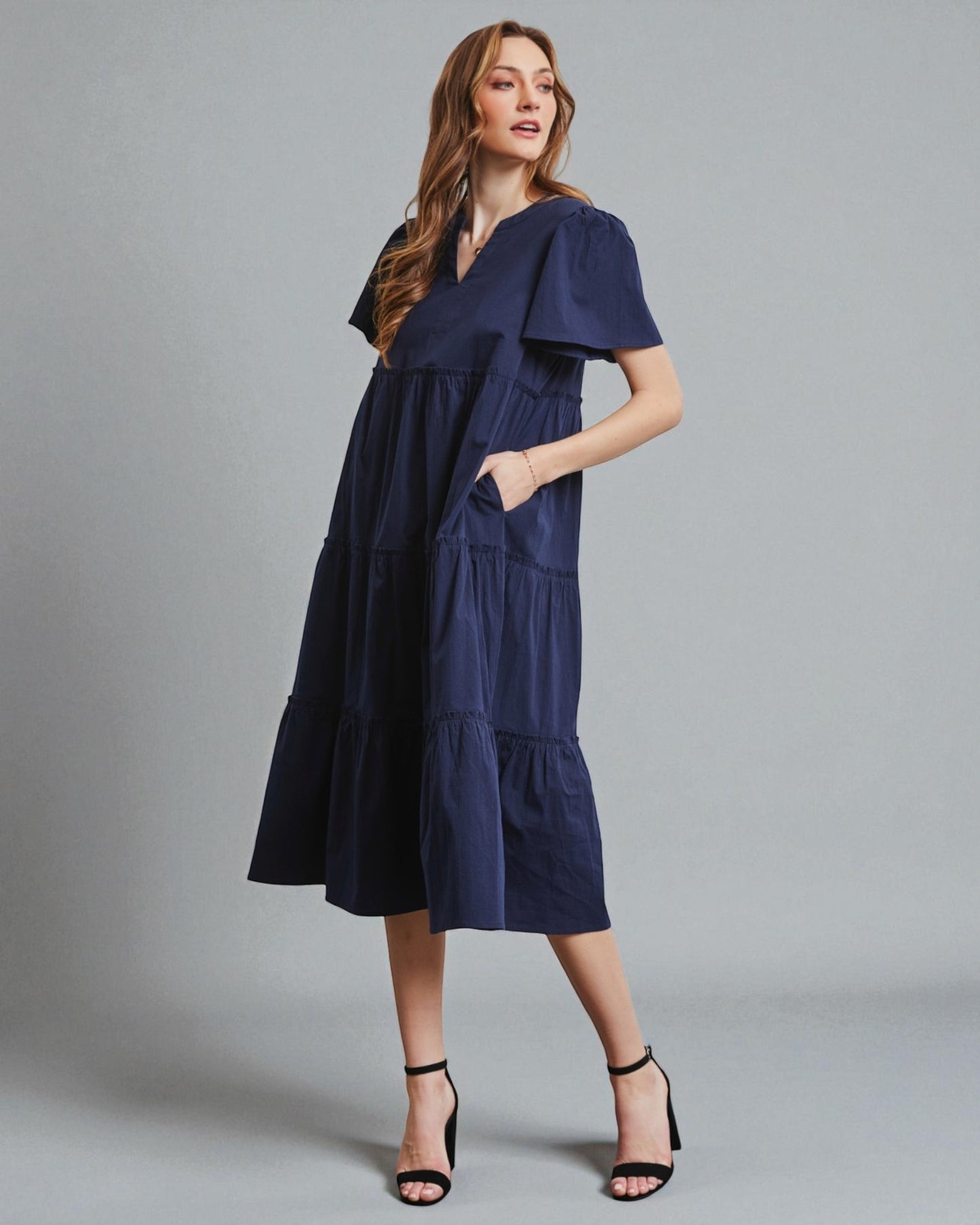 Woman wearing a navy blue dress against a gray background