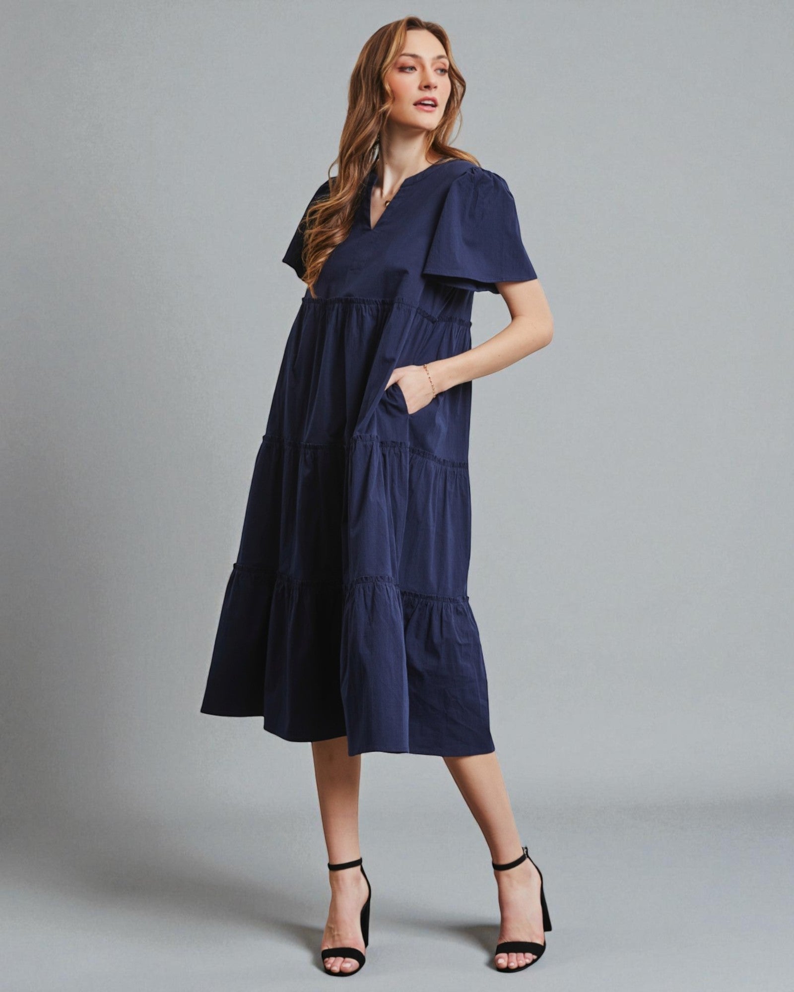 Woman wearing a navy blue dress against a gray background