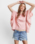 Woman wearing a pink oversized shirt and denim shorts on a white background