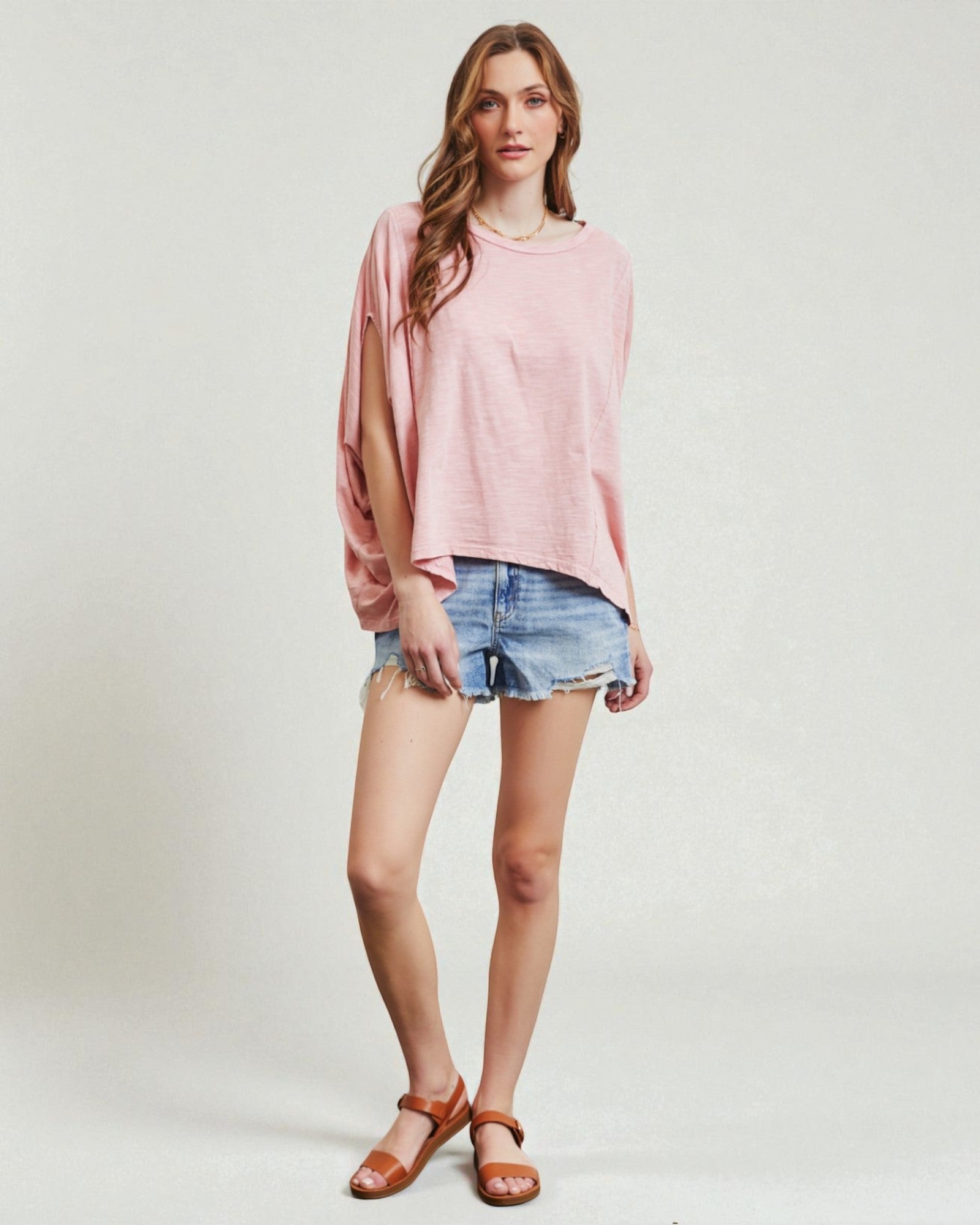 Woman wearing a pink top and denim shorts on a white background