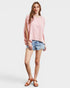 Woman wearing a pink oversized top and denim shorts on a white background
