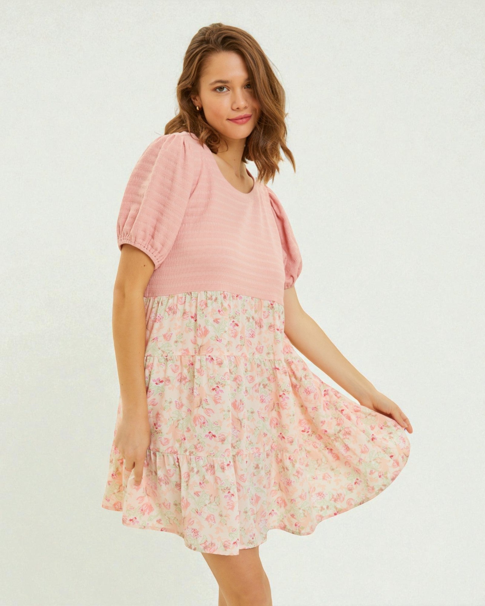 Woman wearing a pink top and floral skirt on a white background