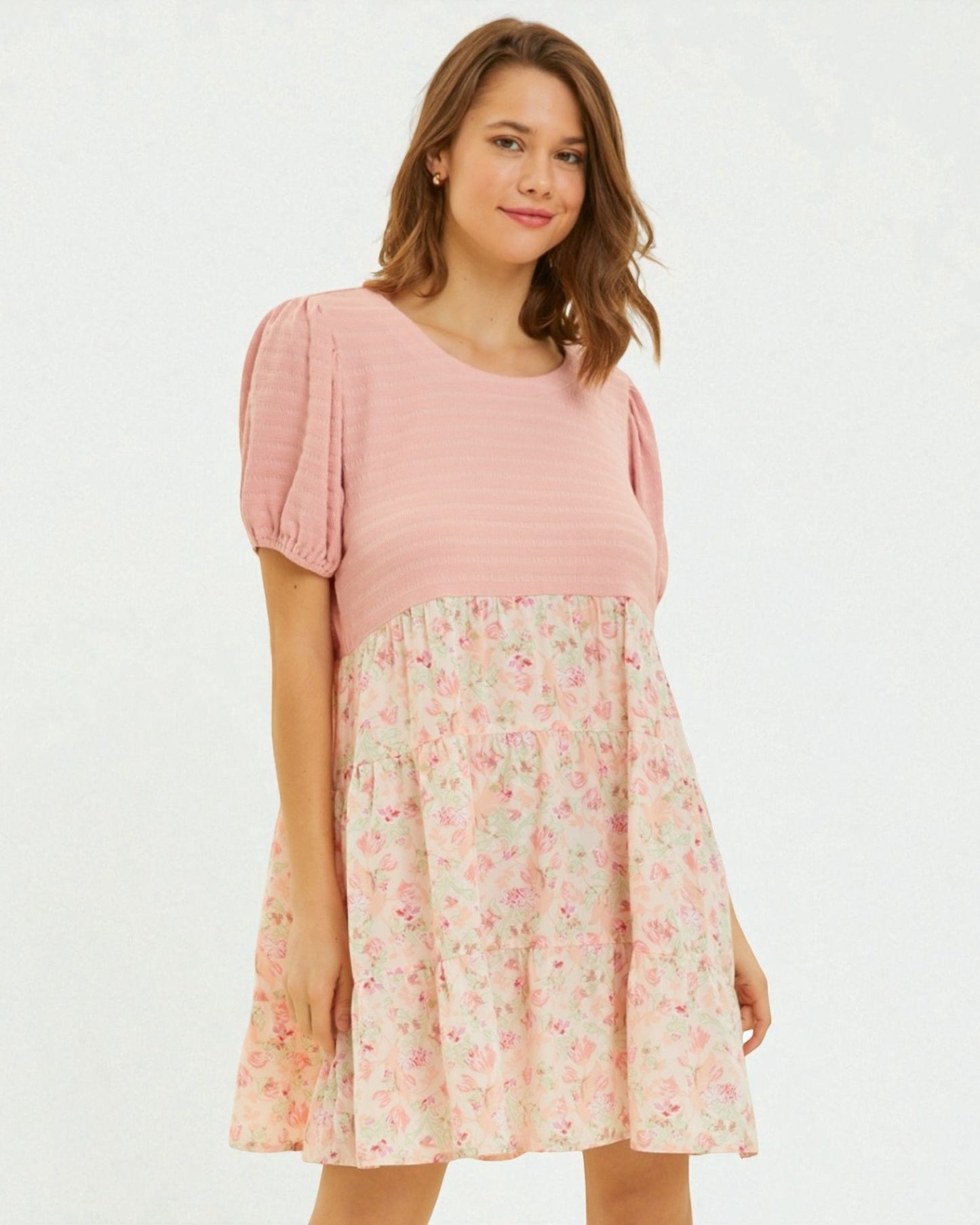 Woman wearing a pink dress with floral skirt on a white background