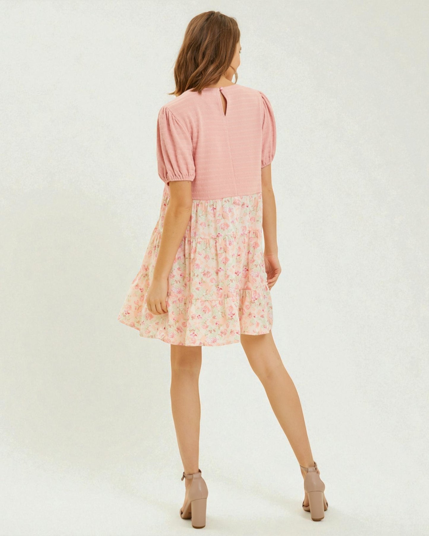 Woman wearing a pink dress with a floral skirt on a white background