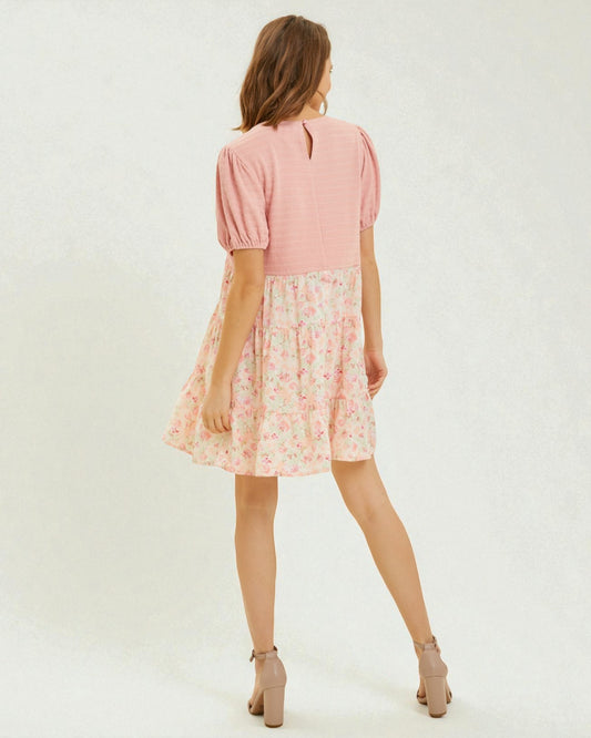 Woman wearing a pink dress with a floral skirt on a white background