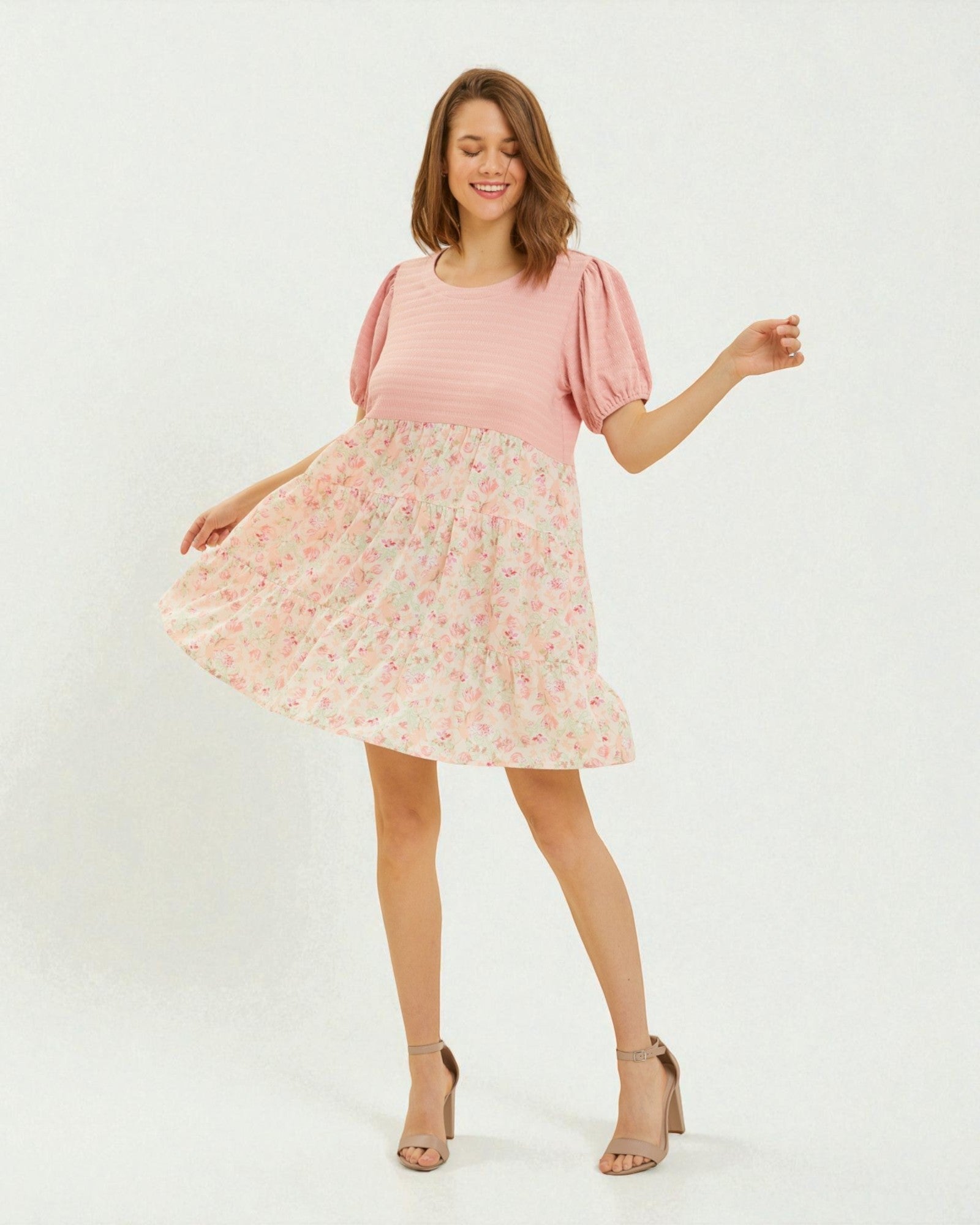 Woman wearing a pink top and floral skirt on a white background