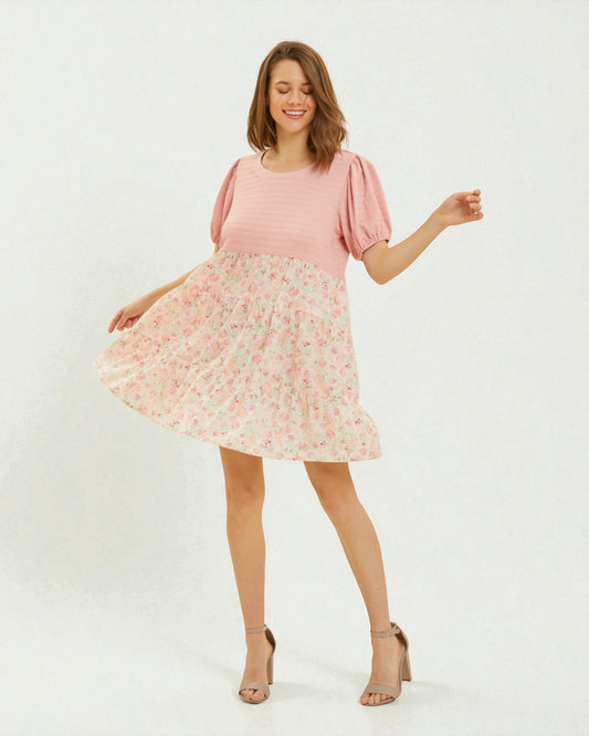 Woman wearing a pink top and floral skirt on a white background