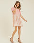 Woman wearing a pink dress with floral pattern on a beige background