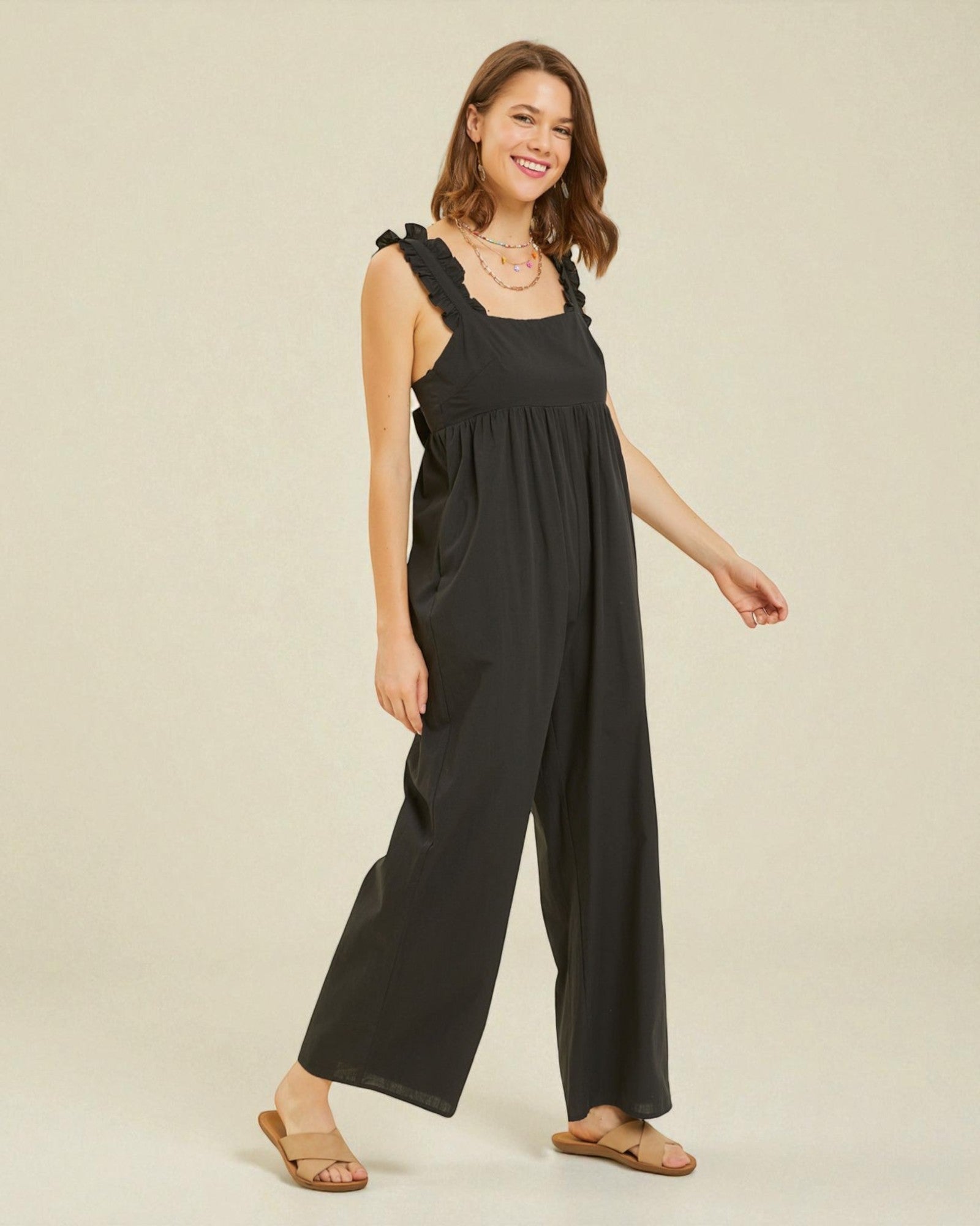 Woman wearing a black jumpsuit on a beige background