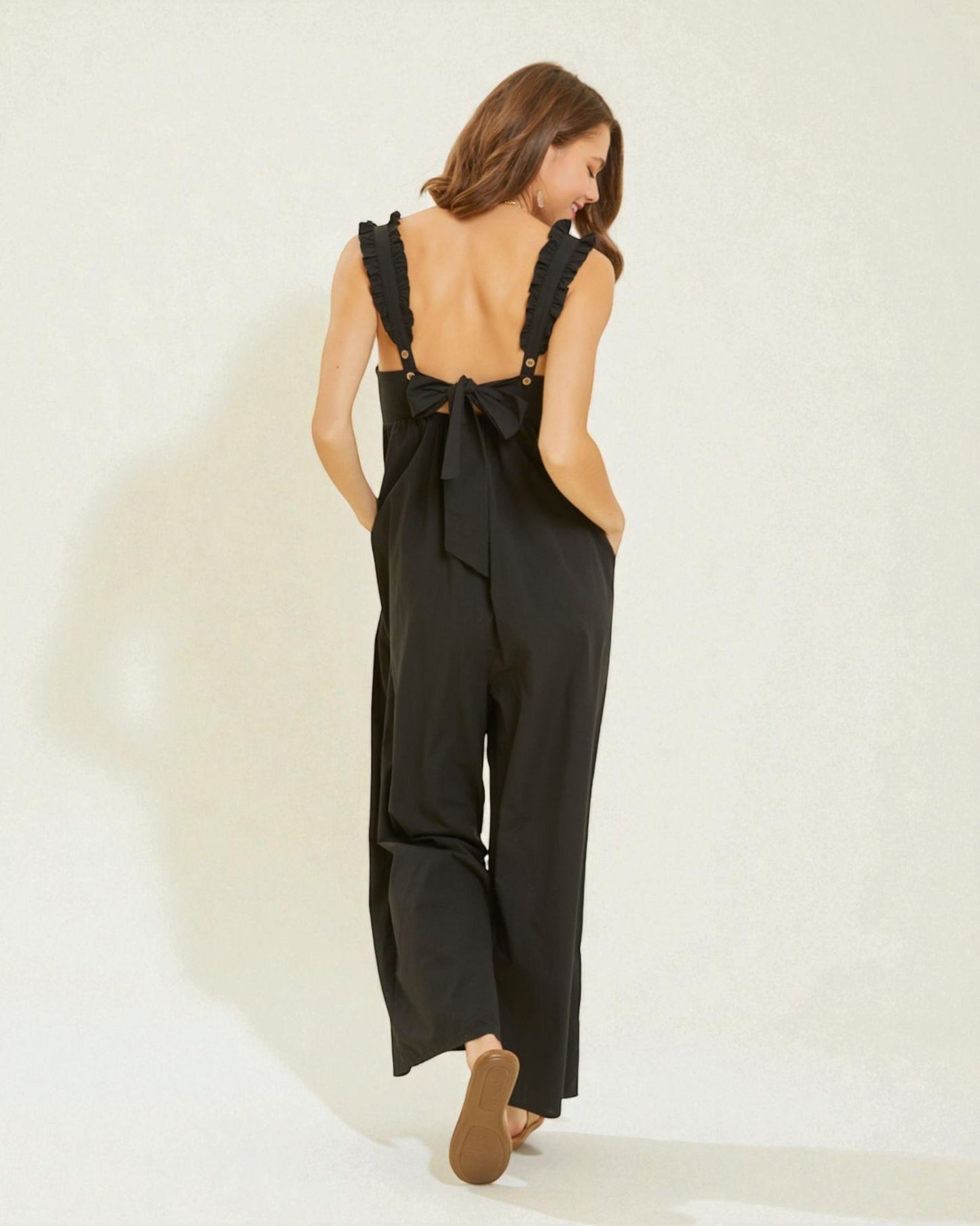 Woman wearing a black jumpsuit with open back on a white background