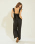 Woman wearing a black jumpsuit with open back on a white background
