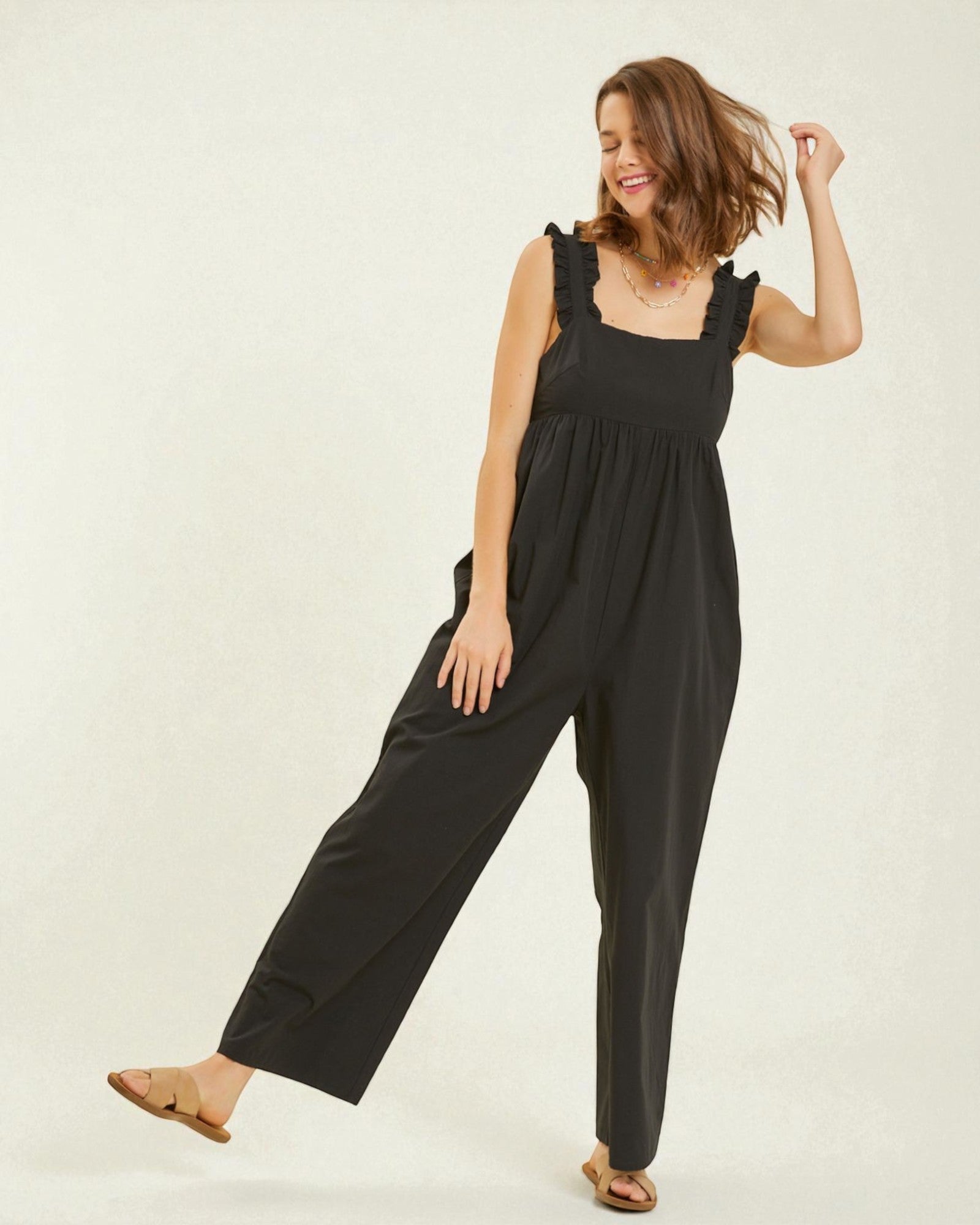 Woman wearing a black jumpsuit on a plain background