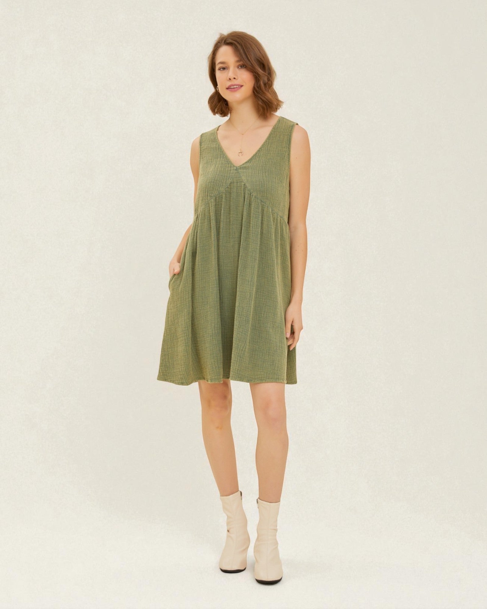Woman wearing a green sleeveless dress on a plain background