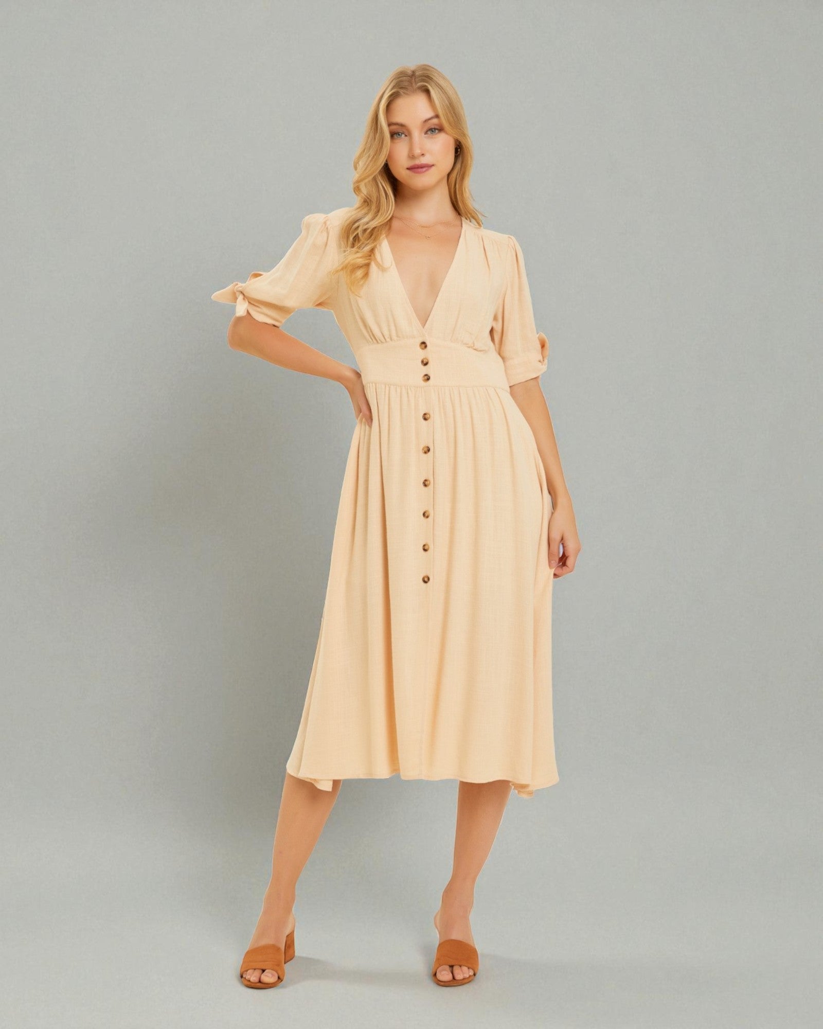 Woman wearing a beige dress with buttons on a gray background
