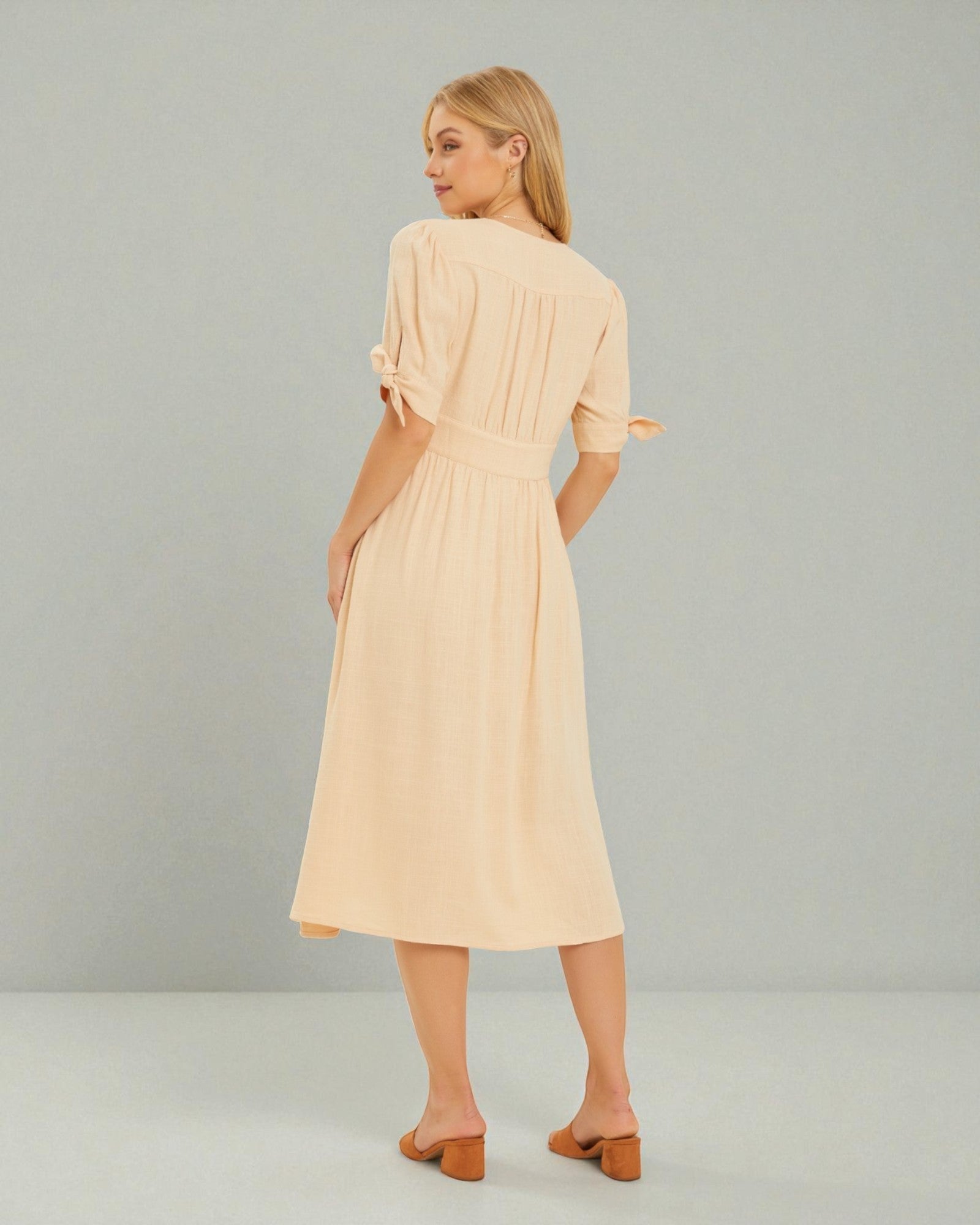 Woman wearing a beige dress against a plain background