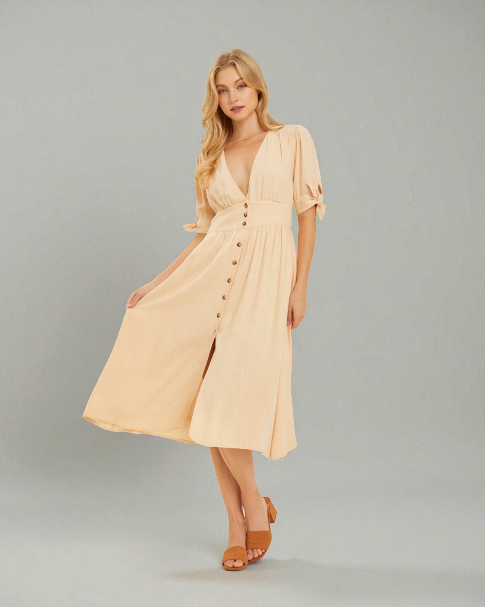 Woman wearing a beige dress with buttons on a gray background
