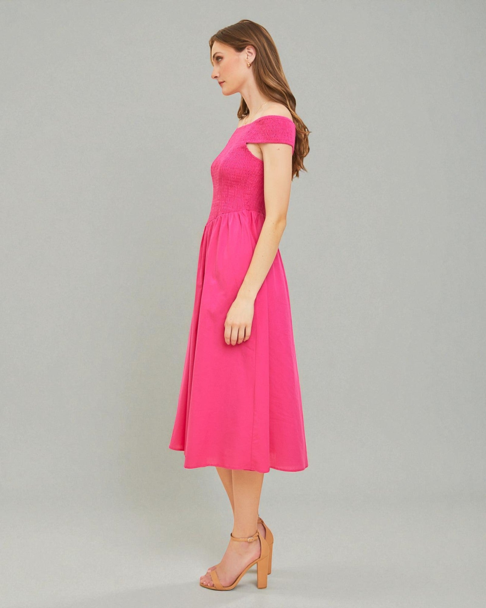 Woman wearing a pink off-shoulder dress on a gray background