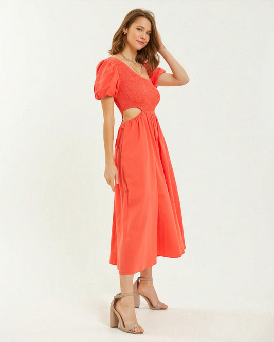 Woman wearing a coral dress with cut-out design on a white background