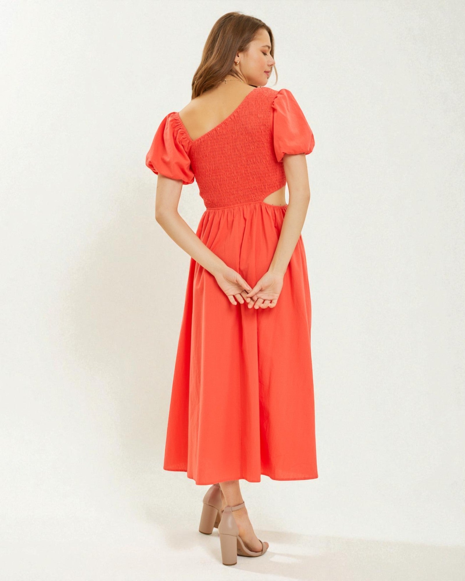 Woman wearing a coral dress with puff sleeves on a white background