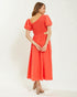 Woman wearing a coral dress with puff sleeves on a white background