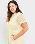 Woman wearing a beige textured romper on a white background