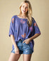 Woman wearing a purple top with butterfly patterns and denim shorts on a beige background