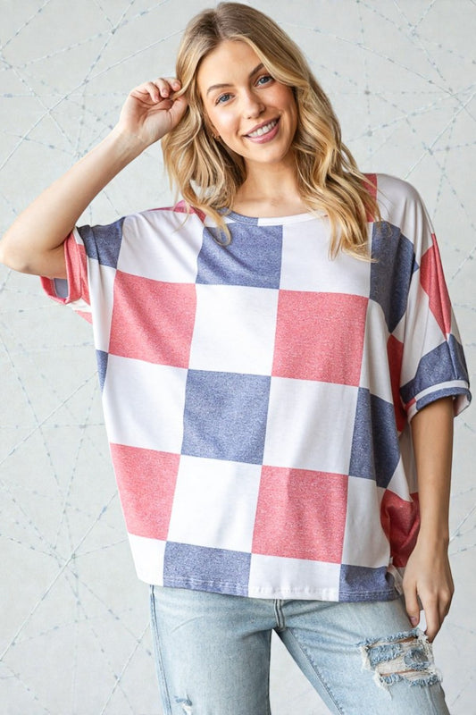 Woman wearing a checkered shirt with red, white, and blue pattern against a light gray background