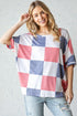 Woman wearing a checkered shirt with red, white, and blue pattern against a light gray background