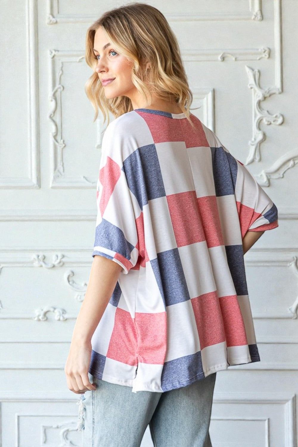 Woman wearing a colorful striped shirt against a white decorative wall.