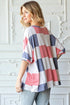 Woman wearing a colorful striped shirt against a white decorative wall.