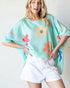 Woman wearing a light blue poncho with colorful flower patterns on a plain background