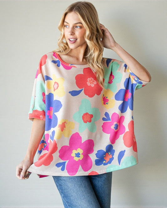Woman wearing a colorful floral sweater against a plain background