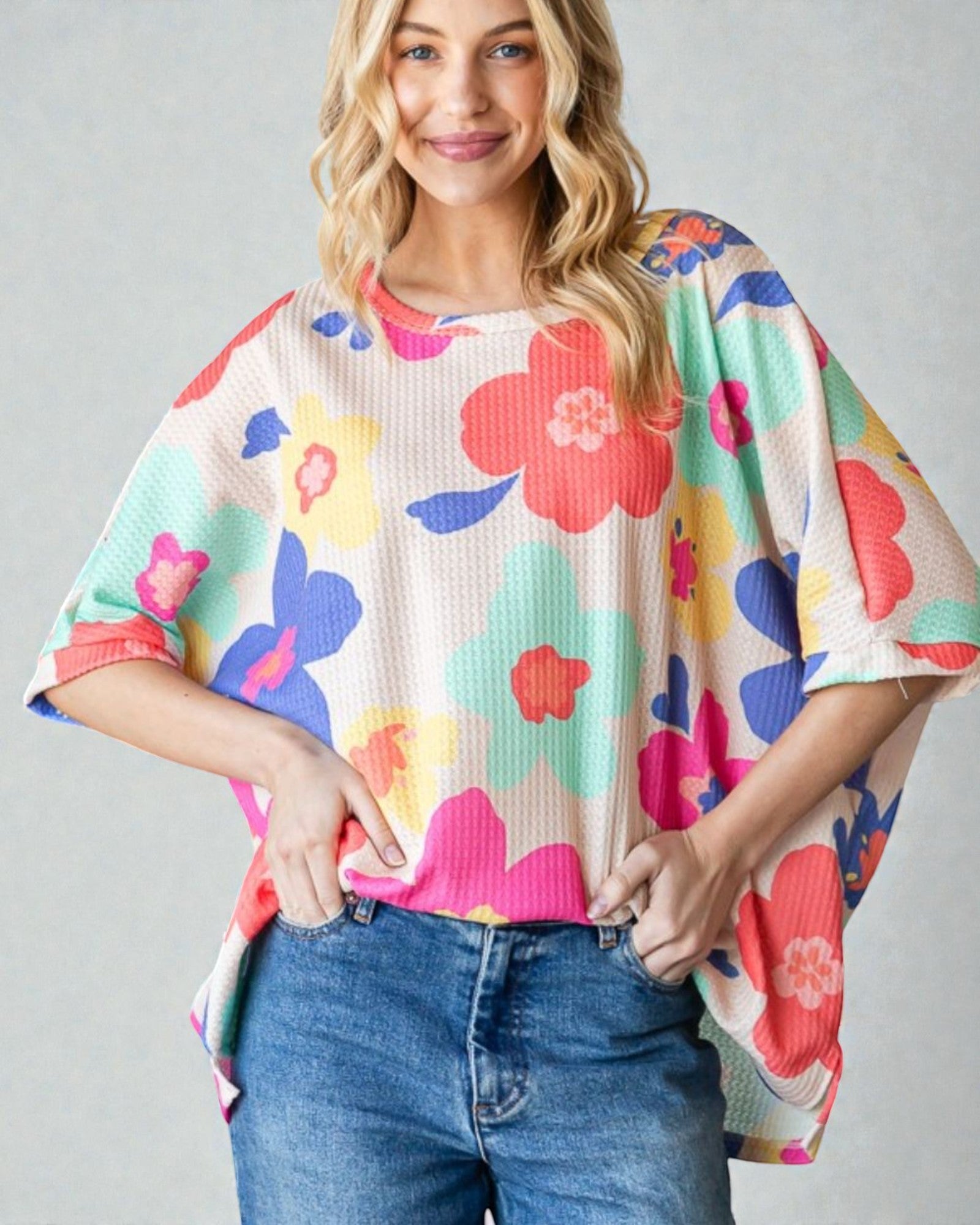 Woman wearing a colorful floral sweater with a plain background