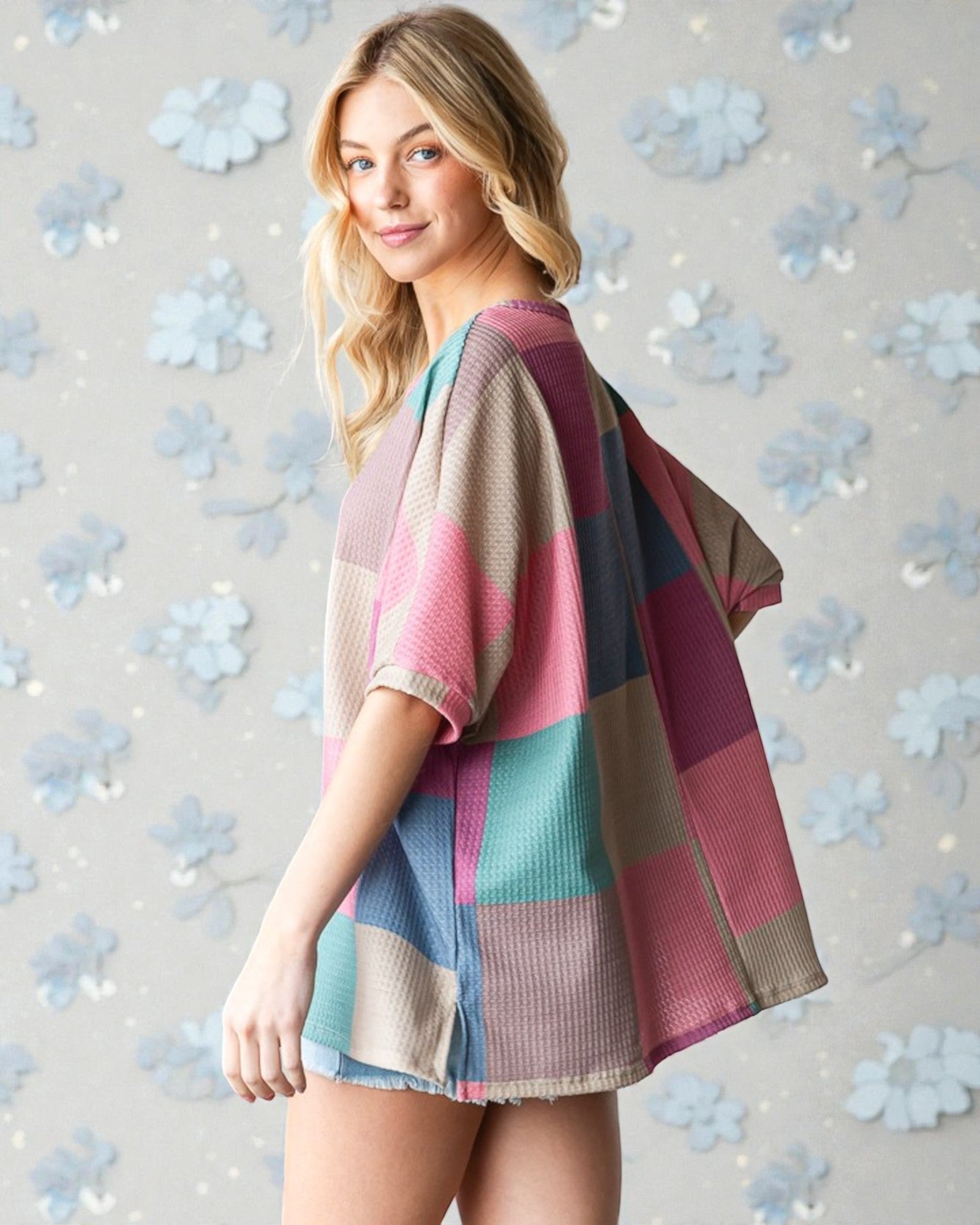 Woman wearing a colorful striped sweater against a floral-patterned background