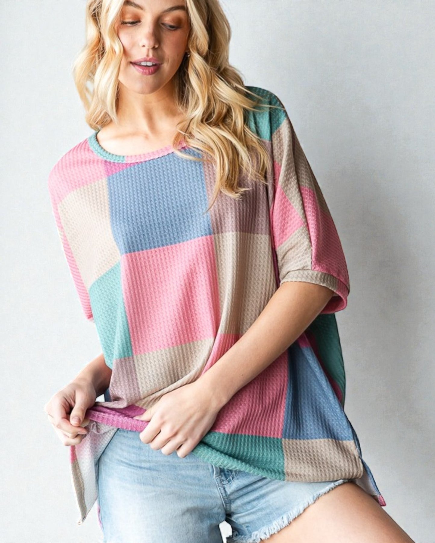 Woman wearing a colorful patchwork sweater against a plain background