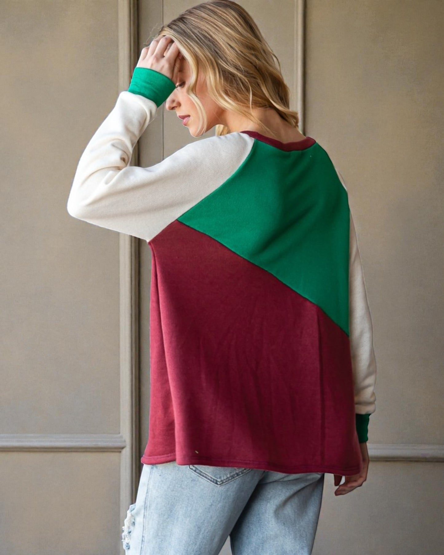 Woman wearing a color-blocked sweater with green and red sections against a neutral background