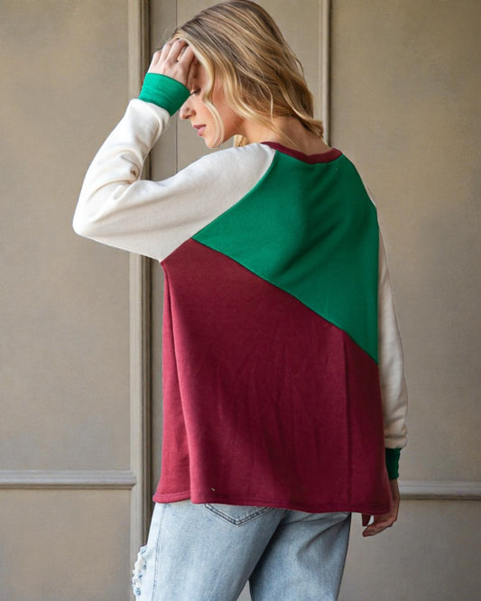 Woman wearing a color-blocked sweater with green and red sections against a neutral background