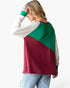 A woman wearing a colorblock long-sleeve top with cream, green, and burgundy panels, paired with light blue jeans, shown from a side-back angle against a plain white background.