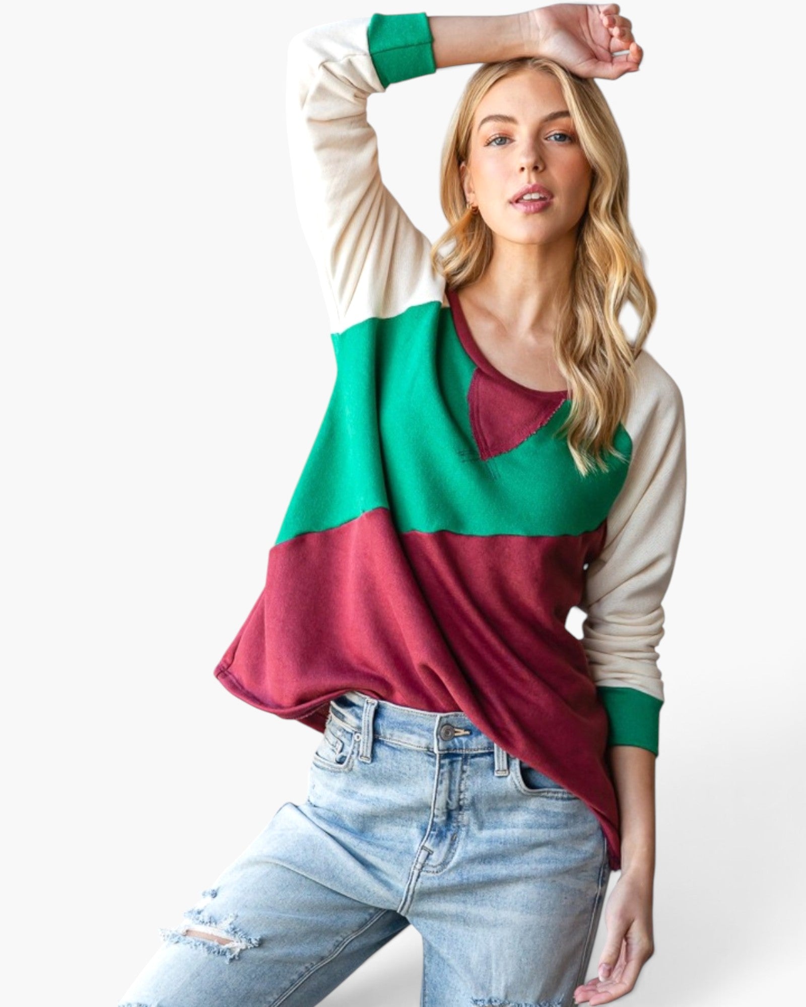 A woman modeling a colorblock long-sleeve top with cream, green, and burgundy color blocks, paired with light-wash distressed jeans against a plain white background.