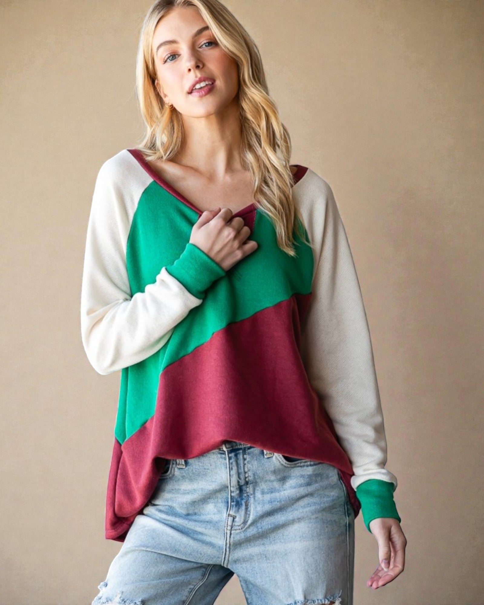 Woman wearing a color-blocked sweater with green, red, and white on a beige background