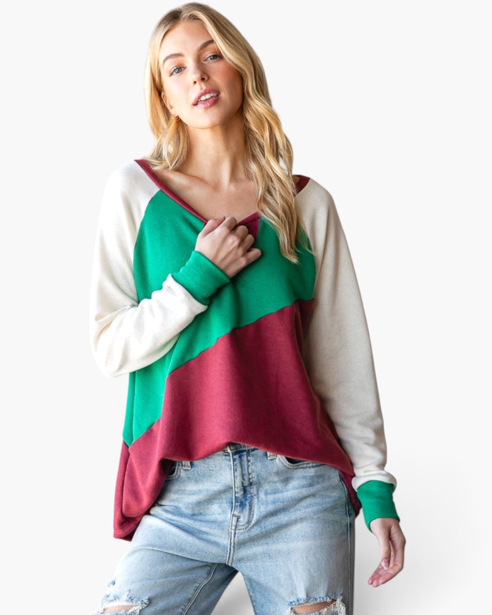 A woman modeling a colorblock long-sleeve top with cream, green, and burgundy panels, paired with light-wash distressed jeans, against a plain white background.