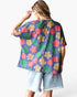 A woman shown from the back wearing a short-sleeve waffle-knit top with a colorful floral pattern in purple, green, red, and beige, paired with light-wash denim shorts against a plain white background.